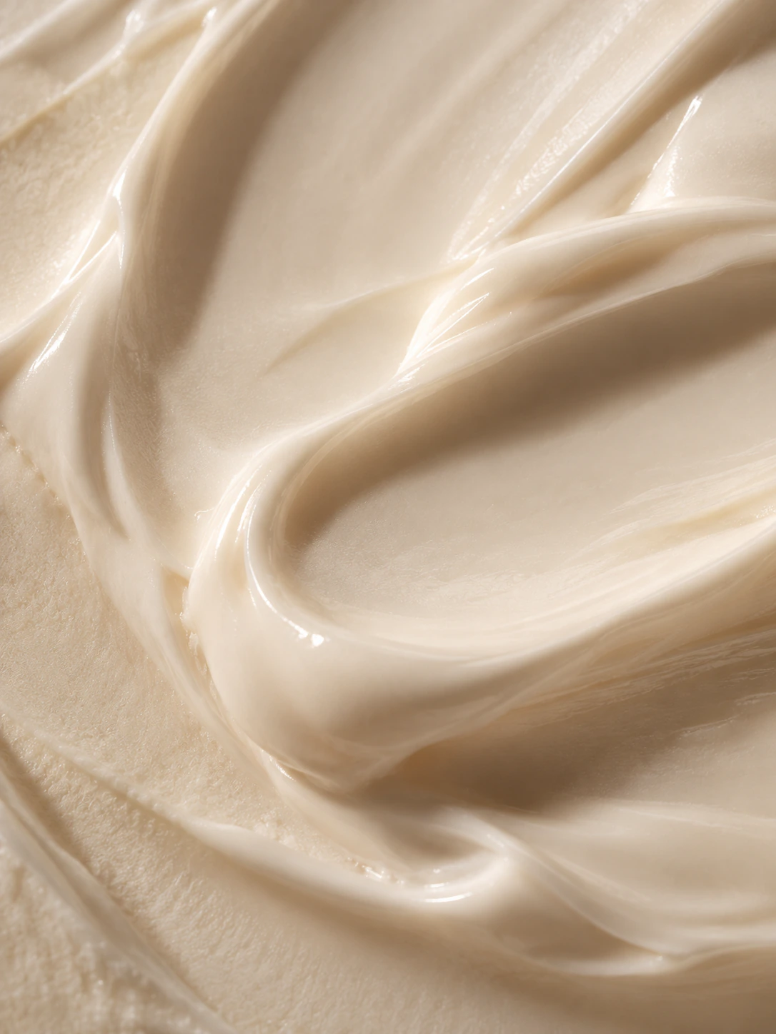 Macro smear of white skincare cream on warm-toned skin